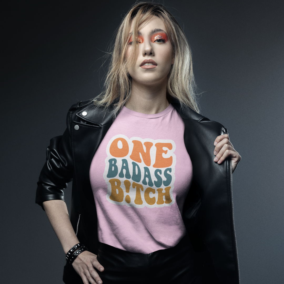 A confident woman stands tall, wearing the "One Badass B!tch" T-shirt from HeadhunterGear. Female empowerment t-shirt